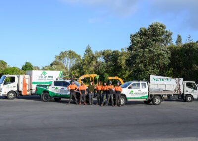 A wide shot image of Elite Arboriculture professionals standing in front of their trucks and tools.
