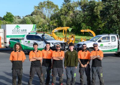 An image of Elite Arboriculture professionals standing in front of their trucks and tools.
